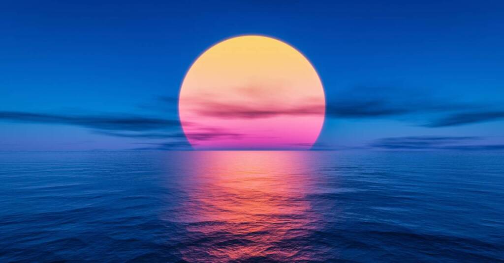 The sun looks orange as it sets over the dark blue water of the ocean. Several clouds are visible in the sky.