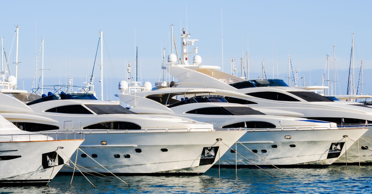 Four luxury yachts anchored next to each other in the bright blue waters of the ocean during the day.